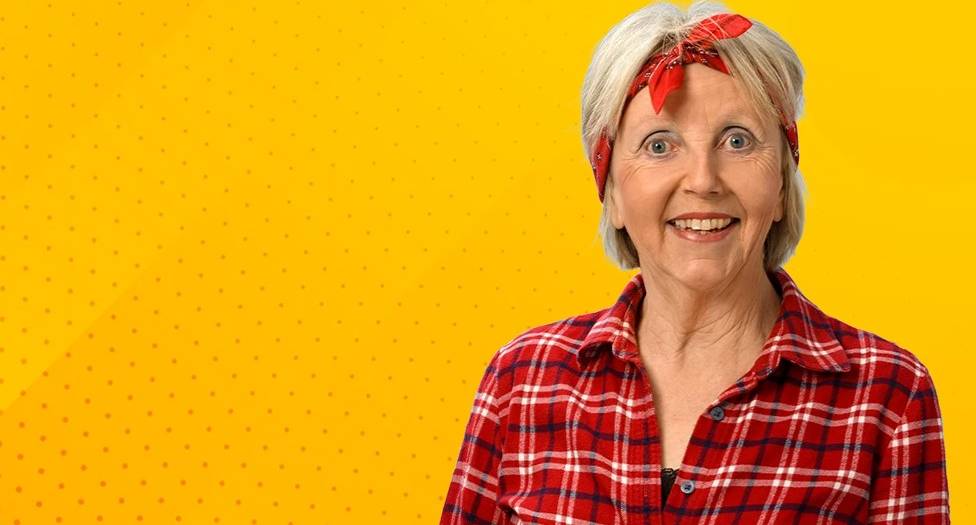 Marianne Schätzle in kariertem Hemd und rotem Kopftuch vor gelbem Hintergrund